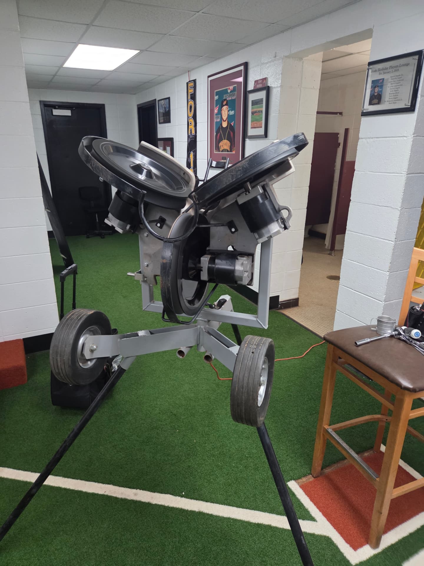 Three-wheel pitching machine with wheels exposed during service