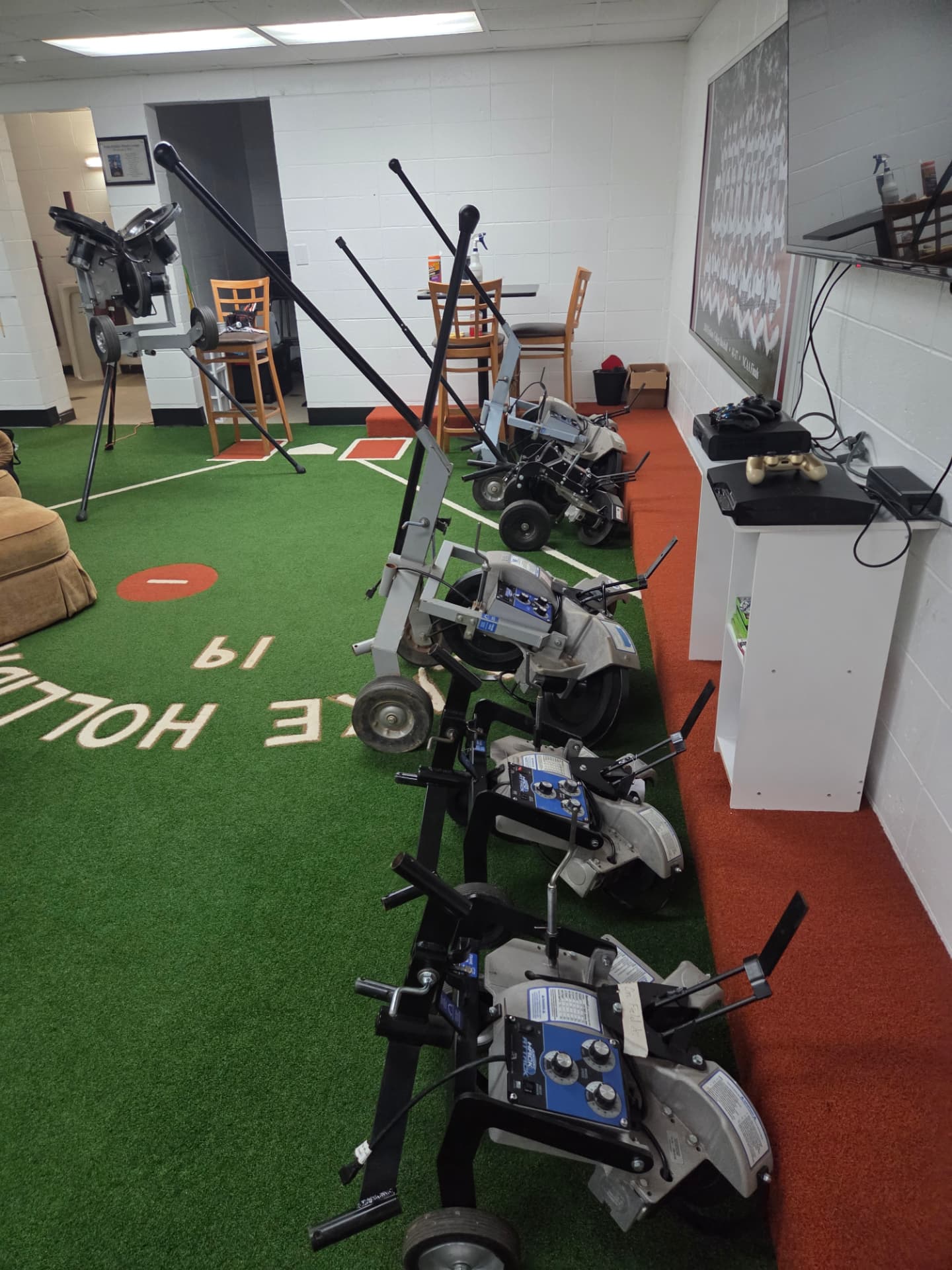 Row of pitching machines lined up for maintenance on indoor turf